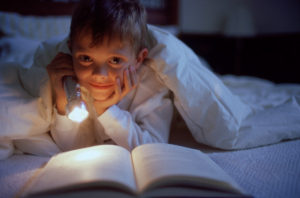 08 Mar 2002 --- Reading in bed with a flashlight --- Image by © Joe Bator/CORBIS