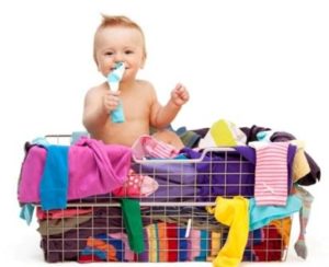 Happy toddler sitting in basket with clothes
